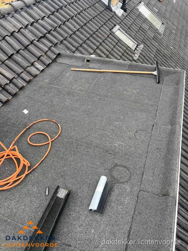 Plat dak reparatie met gereedschap en loodstroken in Lichtenvoorde