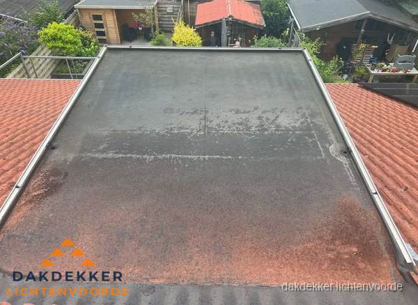 Verouderd plat dak met slijtage tussen schuine daken in Lichtenvoorde Verouderd plat dak met slijtage tussen schuine daken in Lichtenvoorde